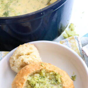 Broccoli soup in bread bowl on white plate