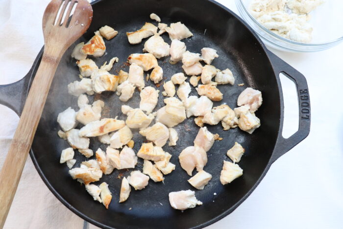 chicken cooking in cast iron skillet