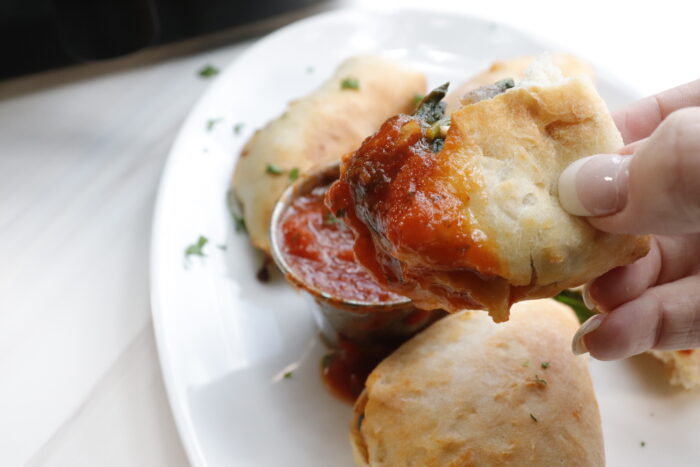 air fryer calzone being dipped in marinara