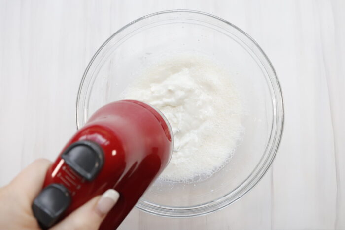 Milk and cream cheese being mixed with hand mixer in a glass bowl for Chocolate mousse