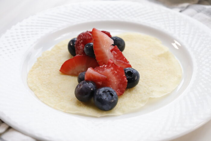 finished breakfast crepes on white plate with berries