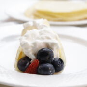 front view of breakfast crepes with berries topped with cool whip