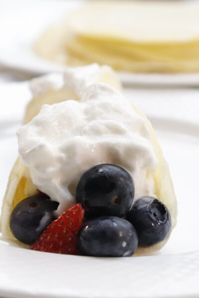 front view of breakfast crepes with berries topped with cool whip