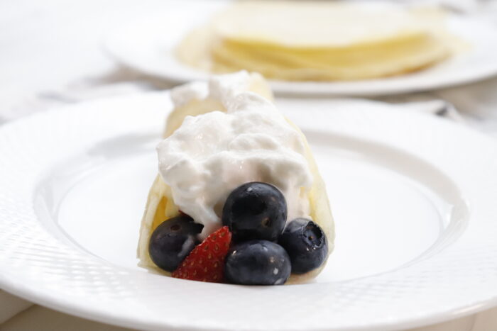 front view of breakfast crepes with berries topped with cool whip