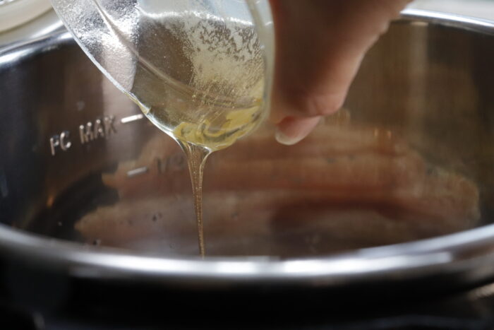 Honey being poured into instant pot for teriyaki chicken