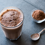 chocolate protein shake in a glass next to spoon