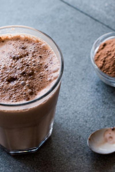 chocolate protein shake in a glass next to spoon