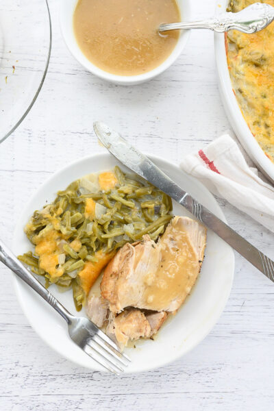 Instant pot turkey breast on white plate next to fork and knife
