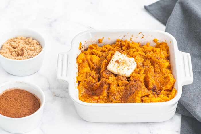 close up of Instant pot thanksgiving mashed sweet potatoes in a casserole dish topped with butter