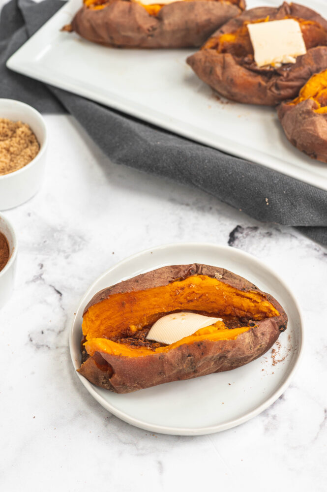 close up of instant pot sweet potato sliced and topped with butter and sugar