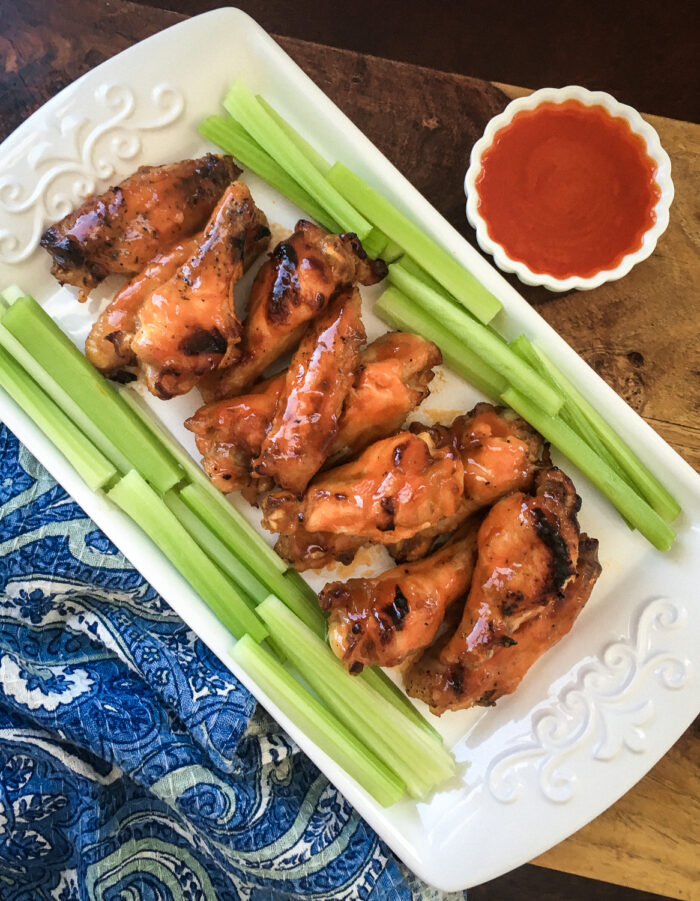 top view of pressure cooker chicken wings next to celery and buffalo sauce