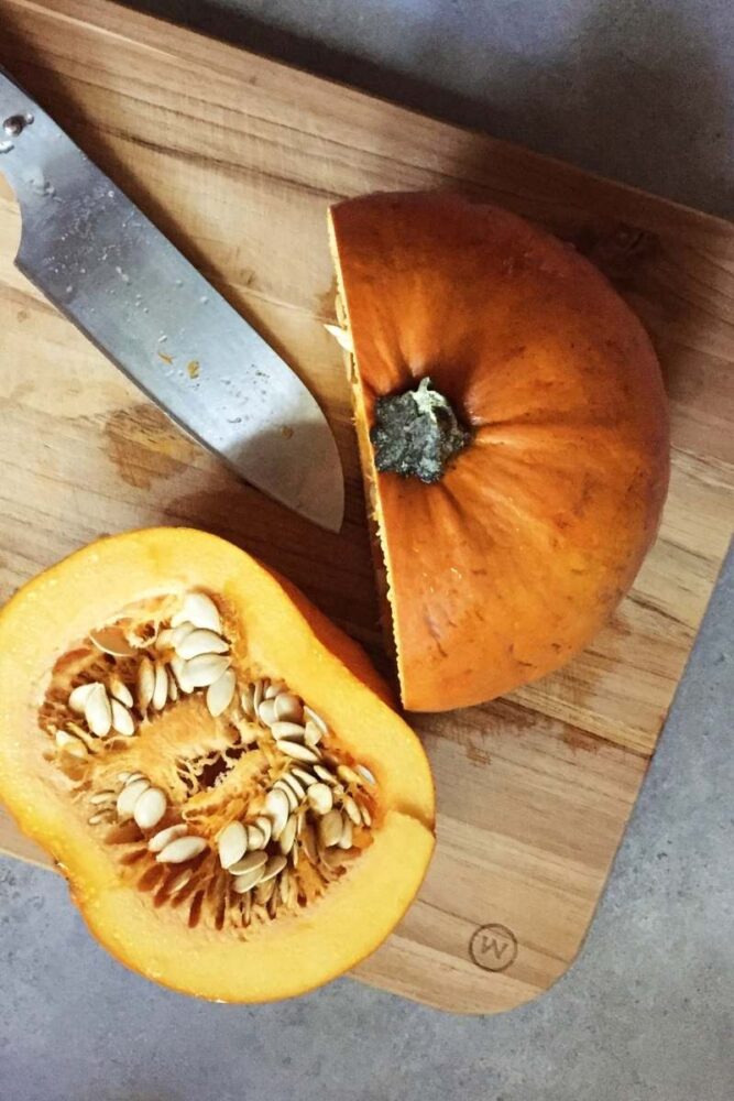 top view of pumpkin cut in half on a cutting board