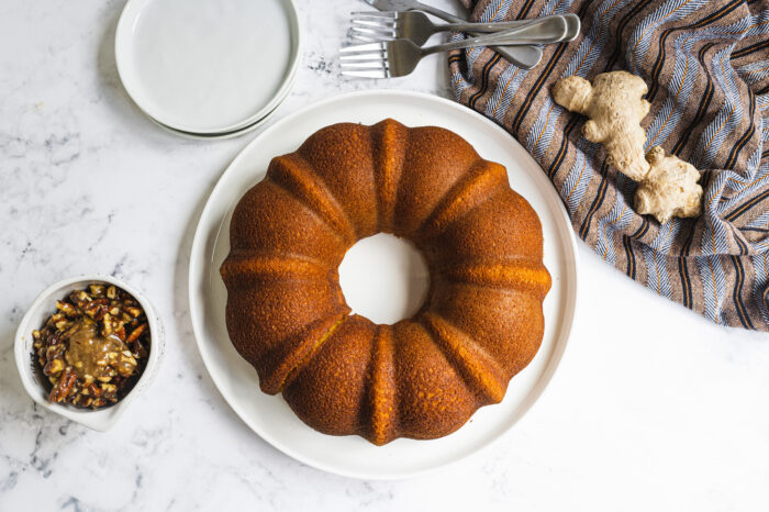 top view of gingerbread bundt cake before drizzle has been added next to a ginger root