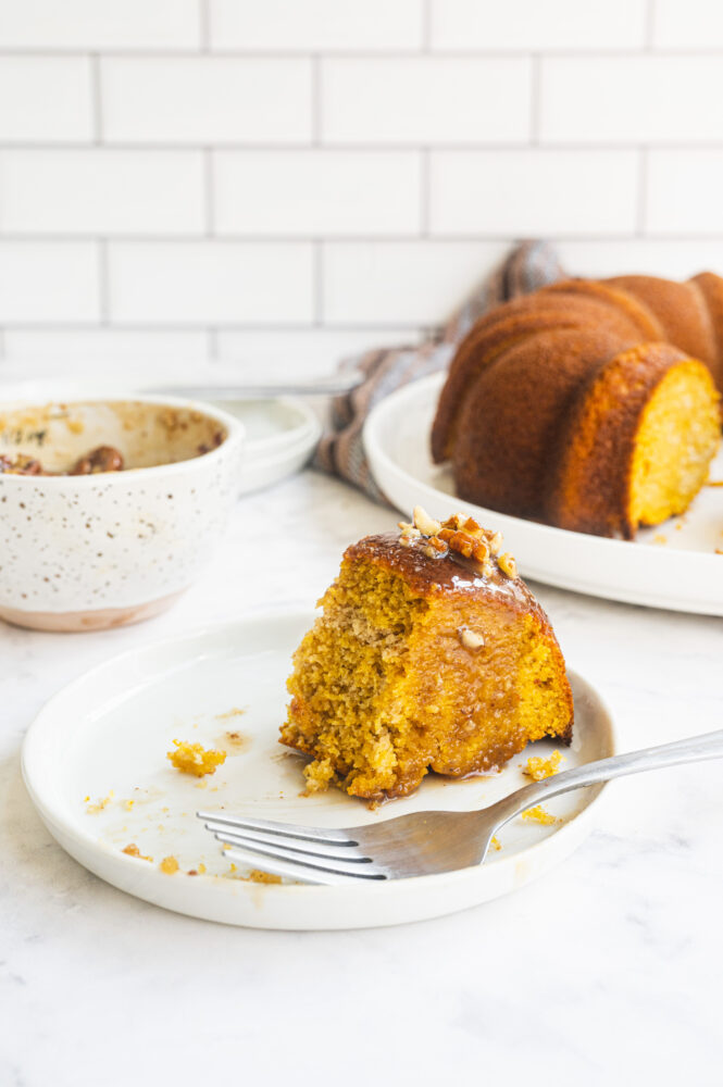 close up of a slice of gingerbread bundt cake topped with homemade caramel drizzle with pecans