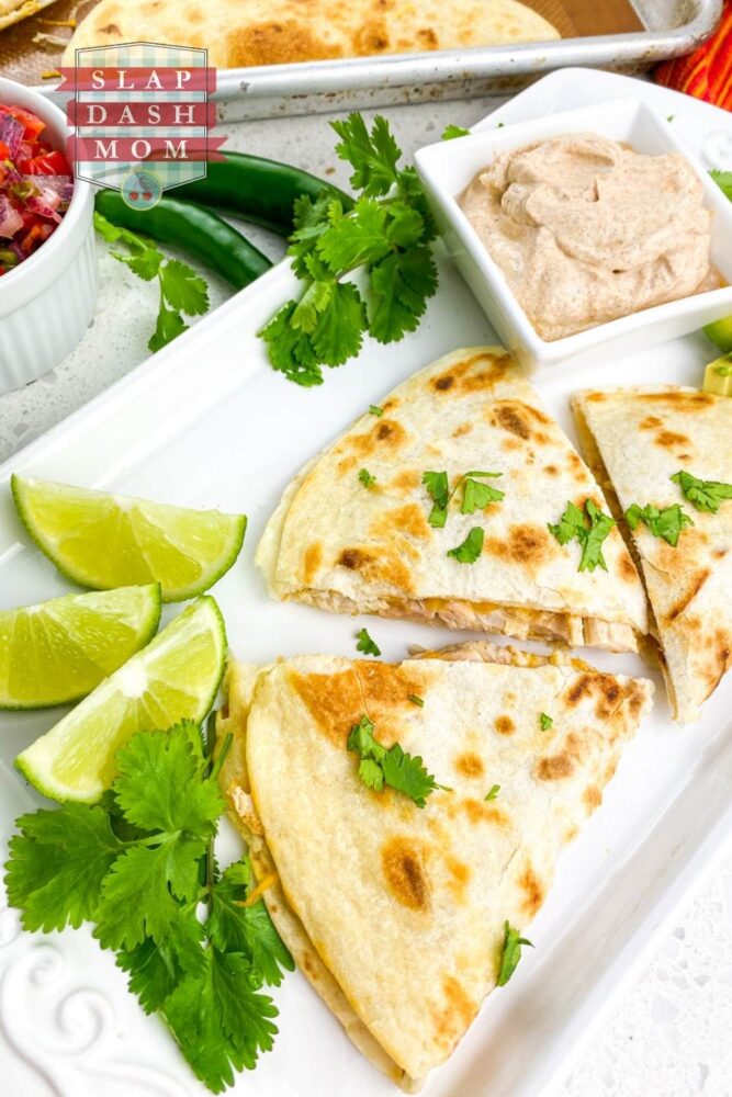 air fryer chicken quesadillas on white plate next to sauce and lime wedges