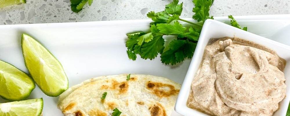 top shot of chicken quesadillas cut in triangles on white plate near salsa