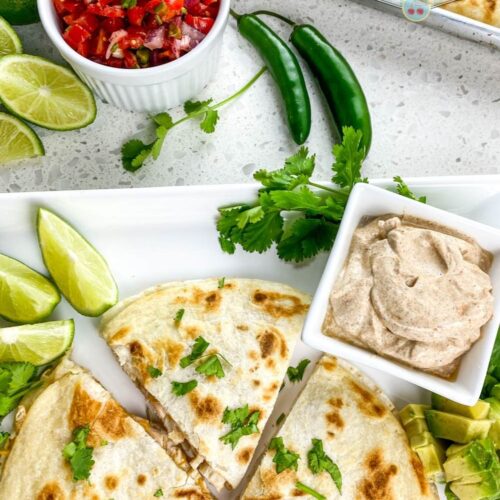 top shot of chicken quesadillas cut in triangles on white plate near salsa