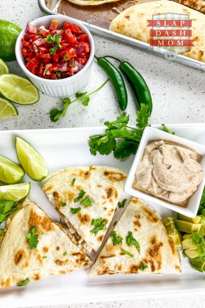 top shot of chicken quesadillas cut in triangles on white plate near salsa