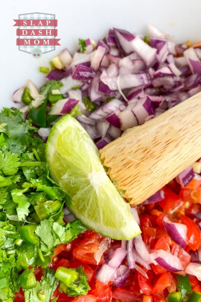 ingredients for pico de gallo in bowl with lime wedge