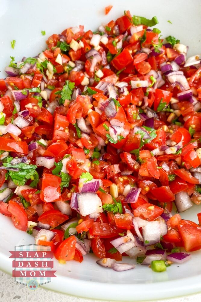 ingredients mixed together in white bowl for pico de gallo without jalapenos