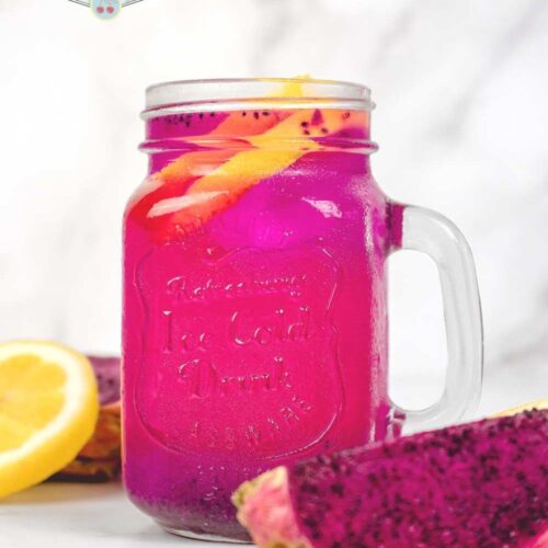 dragon fruit lemonade in a mason jar with handle next to cut dragon fruit