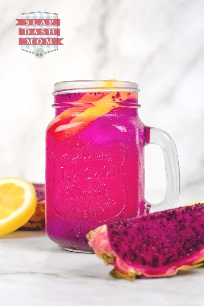 dragon fruit lemonade in a mason jar with handle next to cut dragon fruit