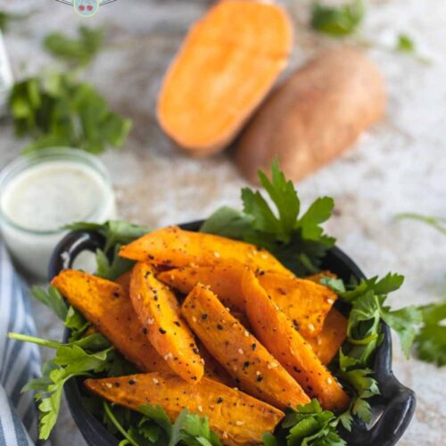 air fried sweet potato wedges in small black bowl with garnish