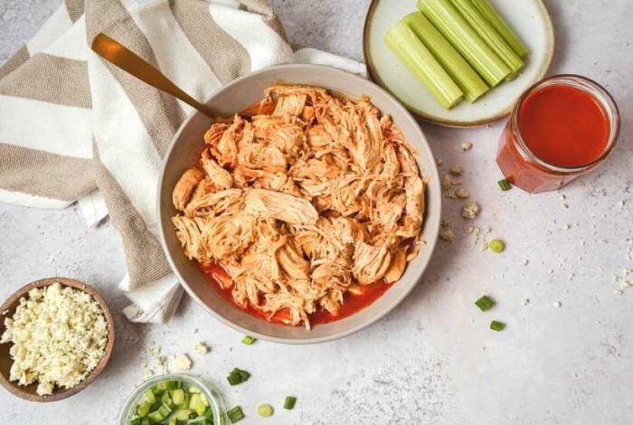 instant pot buffalo chicken next to sauce, celery sticks, and chives